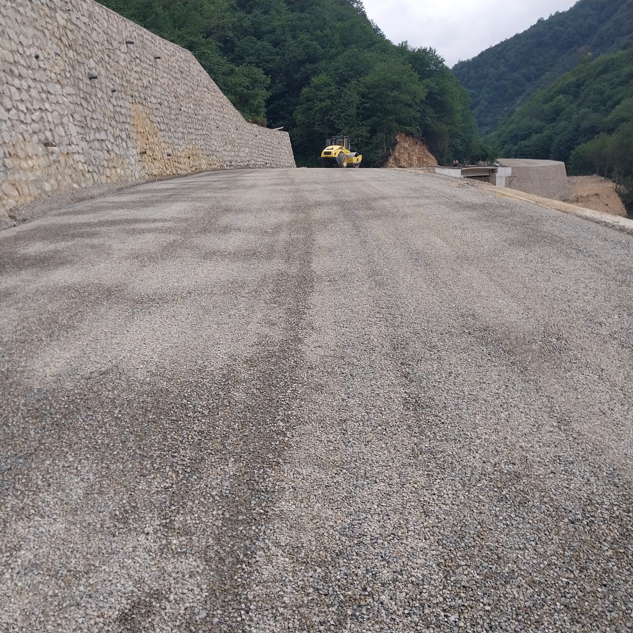 İstinat duvarı yanındaki yol yüzeyinde sıkıştırma çalışması